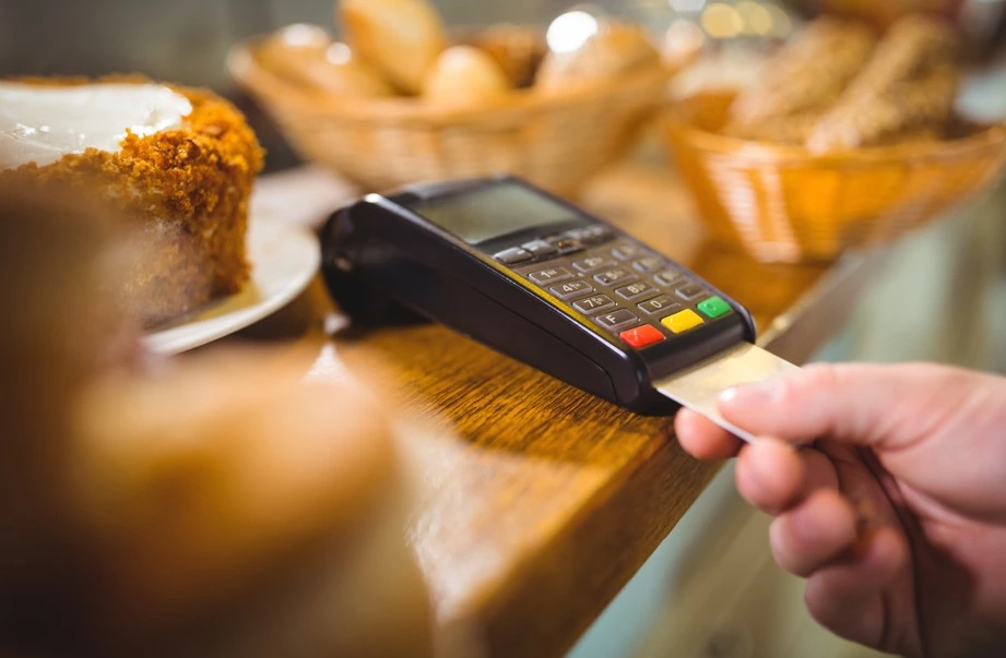 Customer inserting card into POS machine at a bakery counter