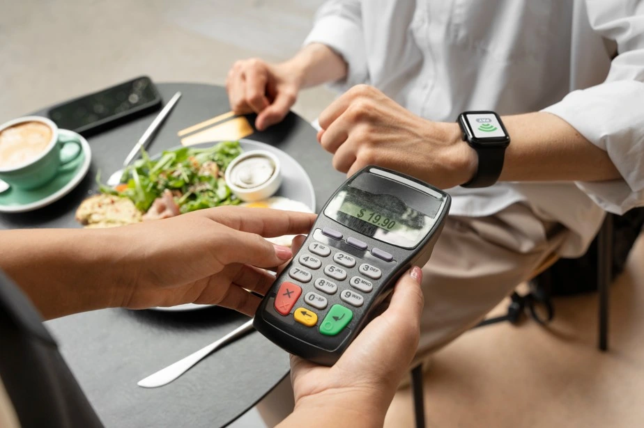Customer paying bill using smartwatch via POS terminal