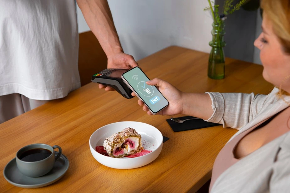 Woman using smartphone for contactless payment at restaurant