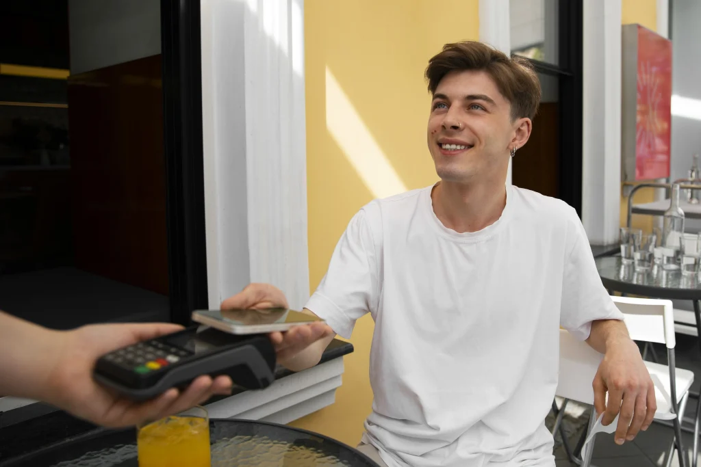 A customer at an outdoor cafe using a smartphone for a contactless payment, demonstrating how POS reporting for sales captures real-time mobile transaction trends.