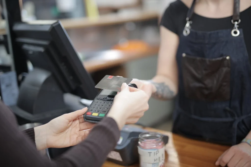 A close-up of a customer tapping a credit card on a compact card reader, highlighting the best POS system for mobile business transactions.