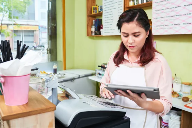 Cafe owner managing sales using POS tablet