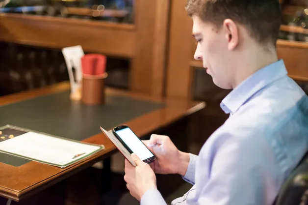 Man using smartphone at a restaurant table